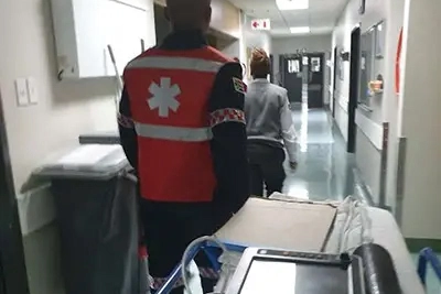 Paramedic transporting patient into hospital corridor